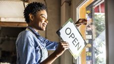 A small business owner flips the open sign on the door of her business.