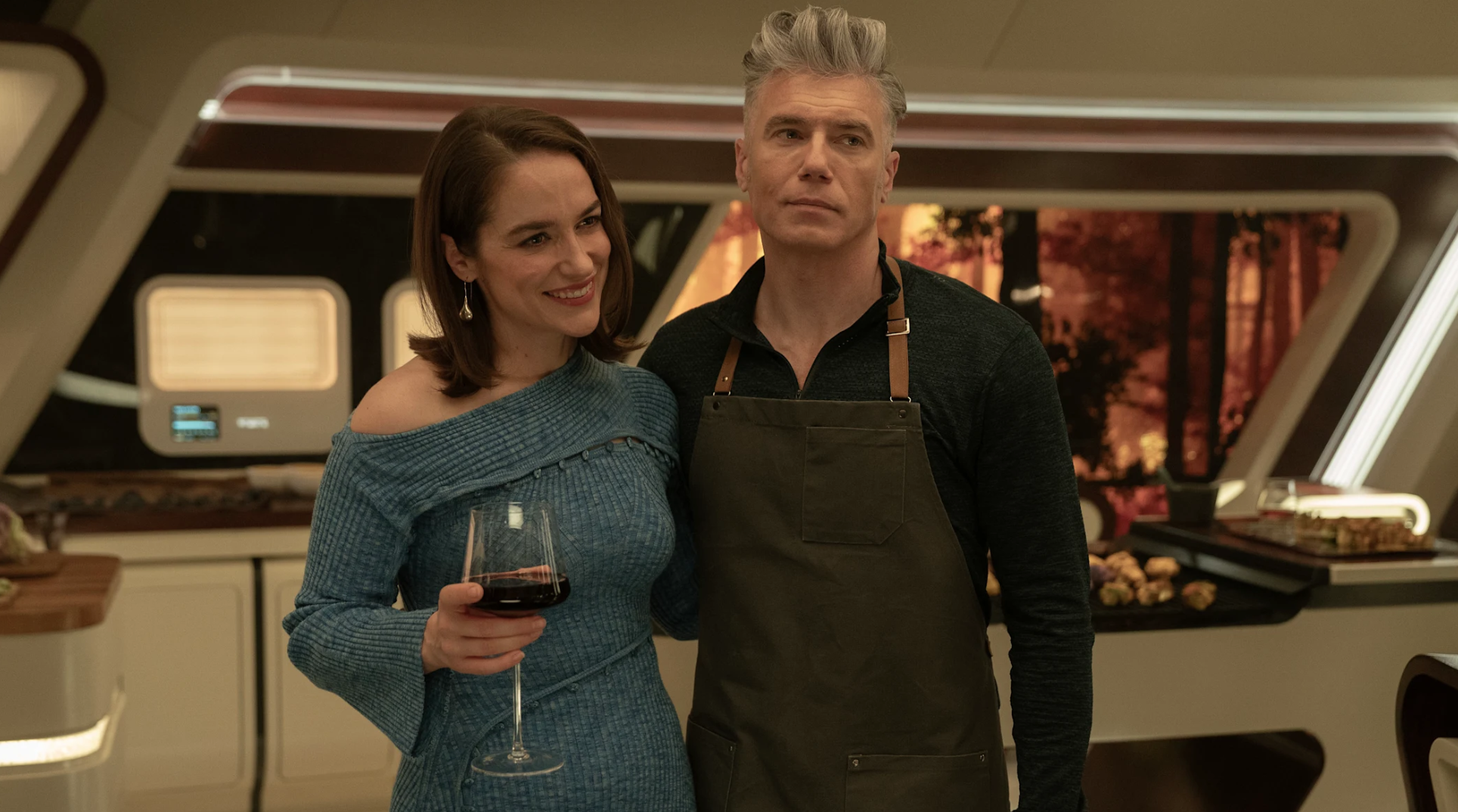 a man and woman stand in a kitchen making dinner