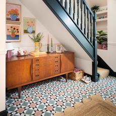 A hallway with a patterned tiled floor and a midcentury modern sideboard