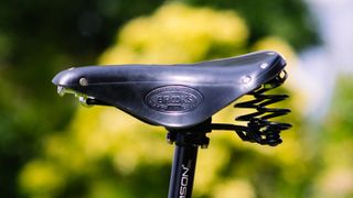 A close up of a black leather saddle with large springs at the rear