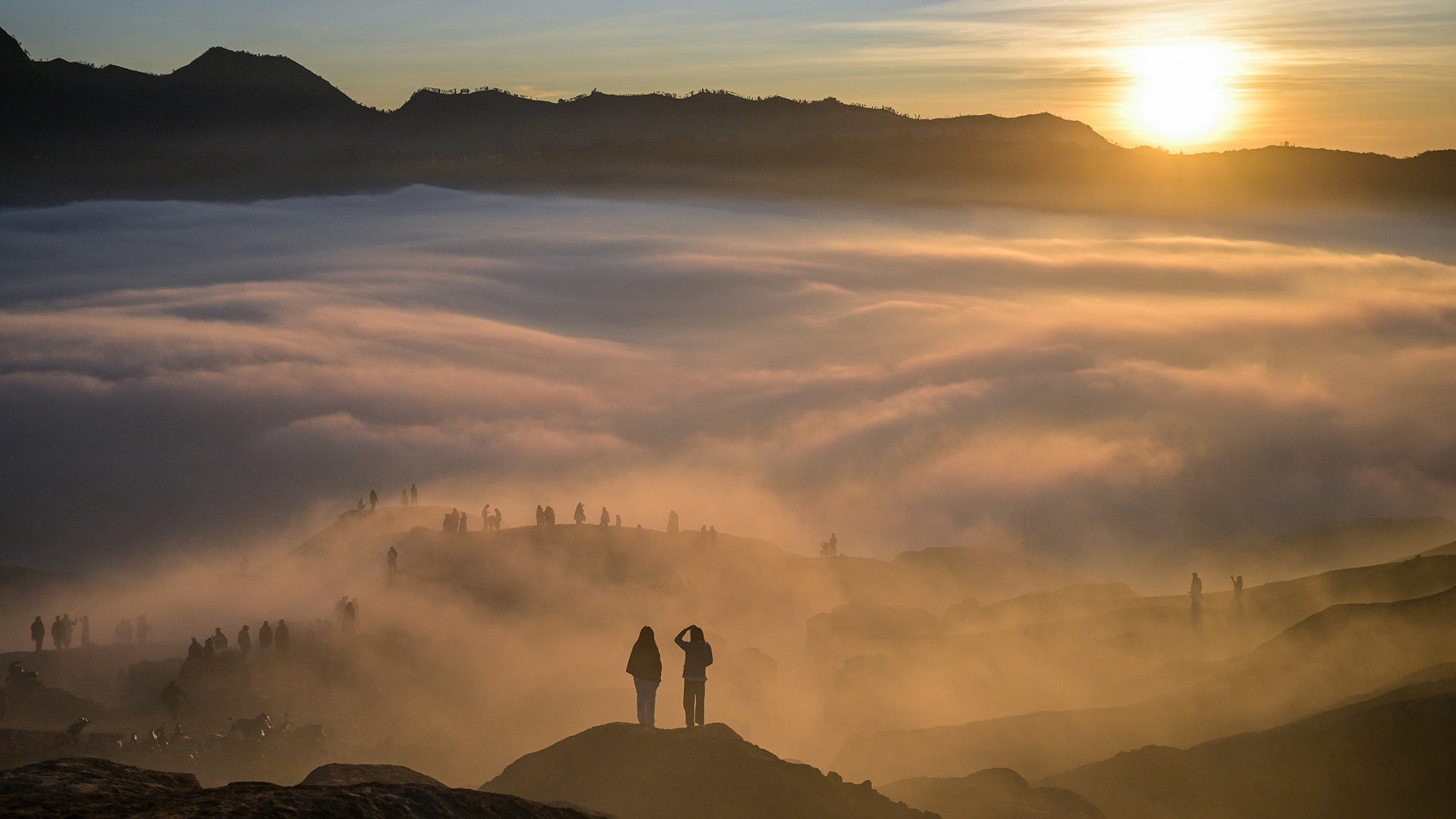 Hindu devotees are seen through low-lying clouds at sunrise as they ascend the active Mount Bromo volcano near Probolinggo, East Java
