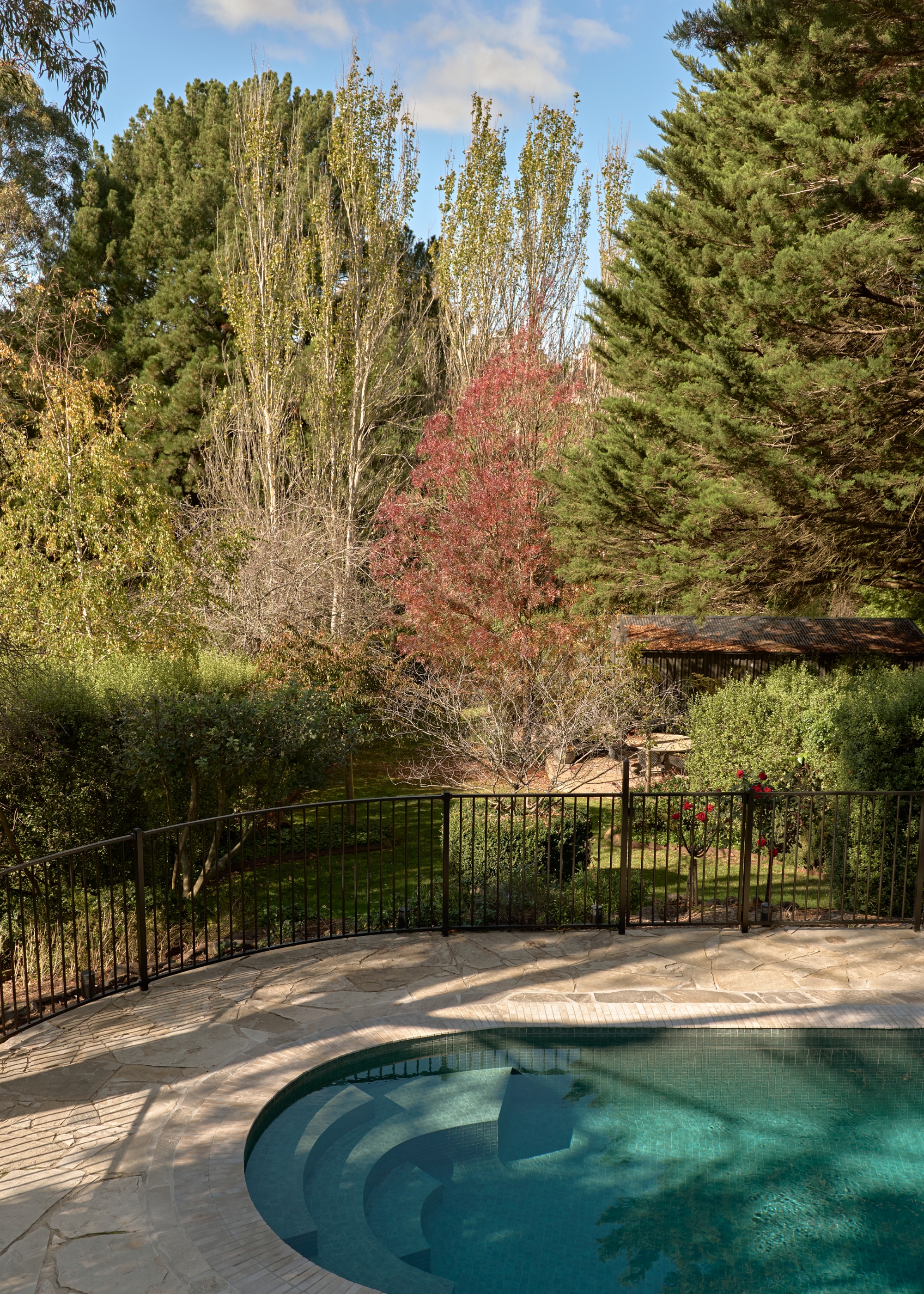 An outdoor garden and pool area with a black gated fence