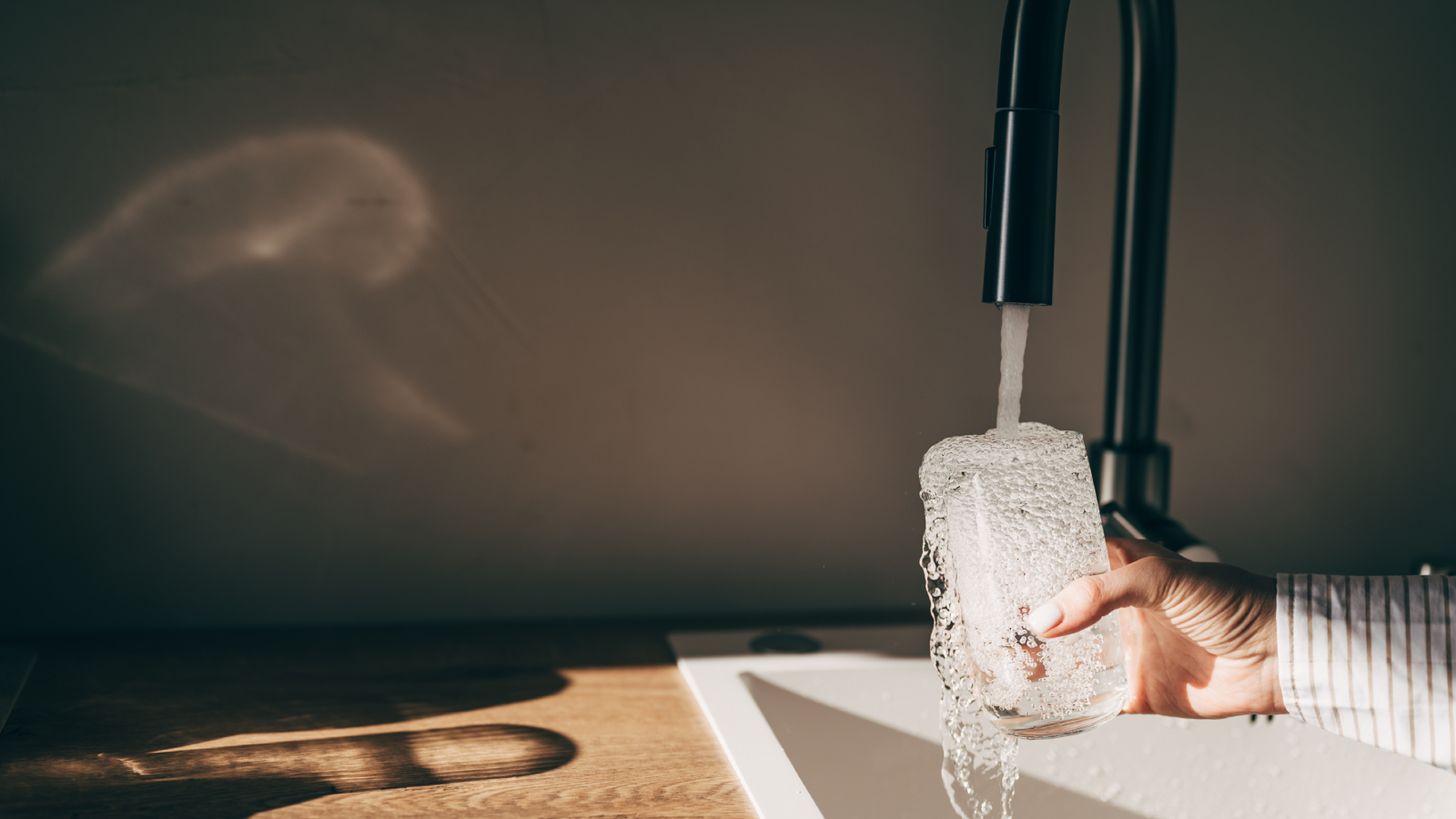 hand holding glass under running kitchen tap