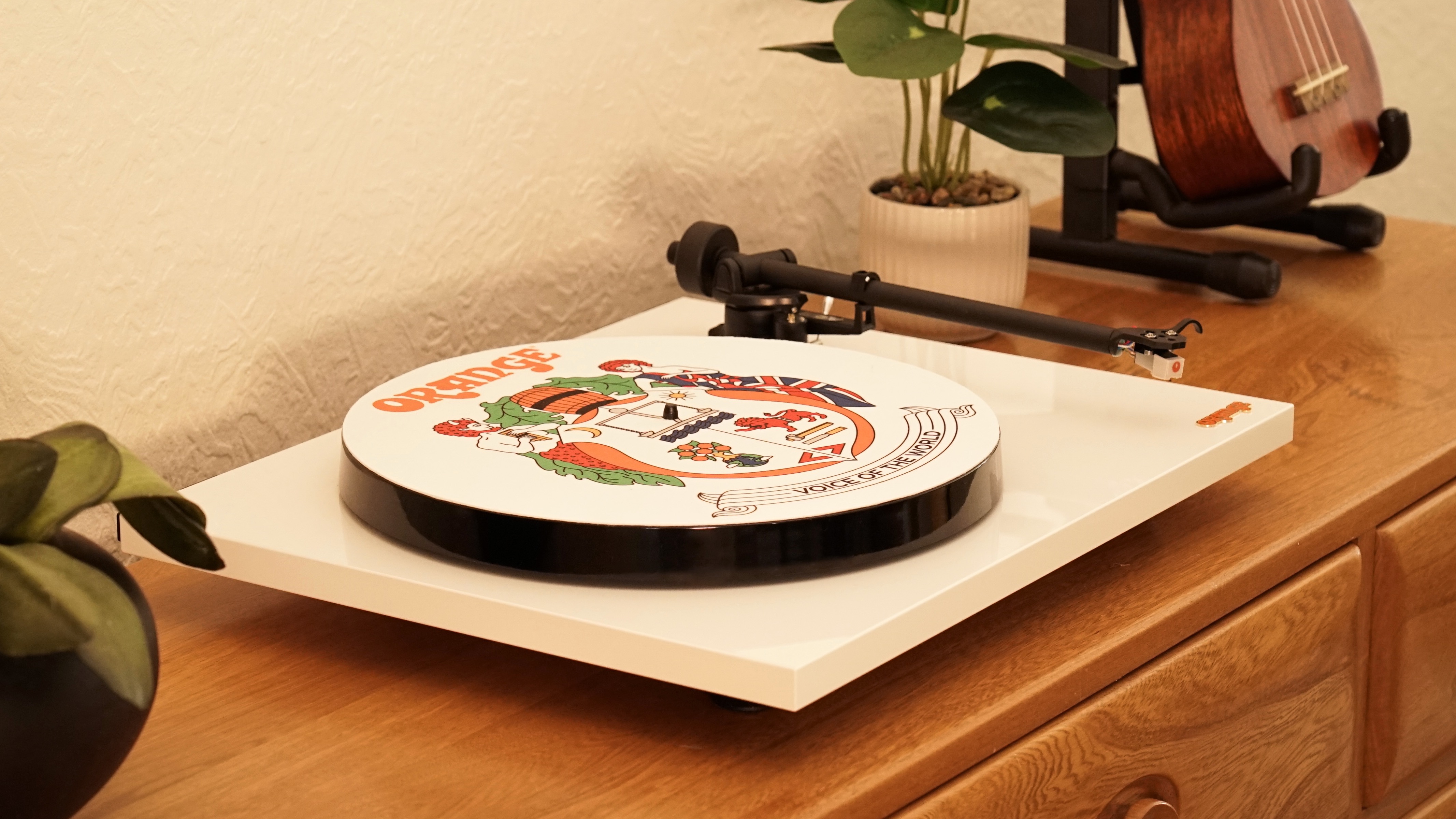 The O Turntable from Orange Amps, on a wooden cabinet between two pot plants.