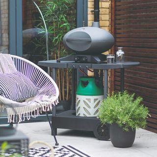 A patio with a gas pizza oven and a garden chair