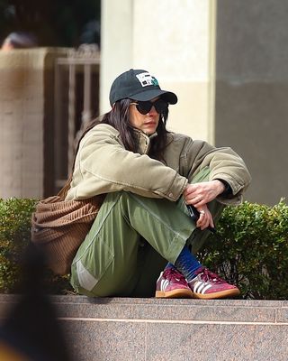 Anne Hathaway wears burgundy adidas sambas styled with green cargo pants and a khaki padded jacket