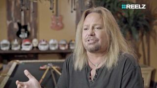 Vince Neil sitting in front of a pool table
