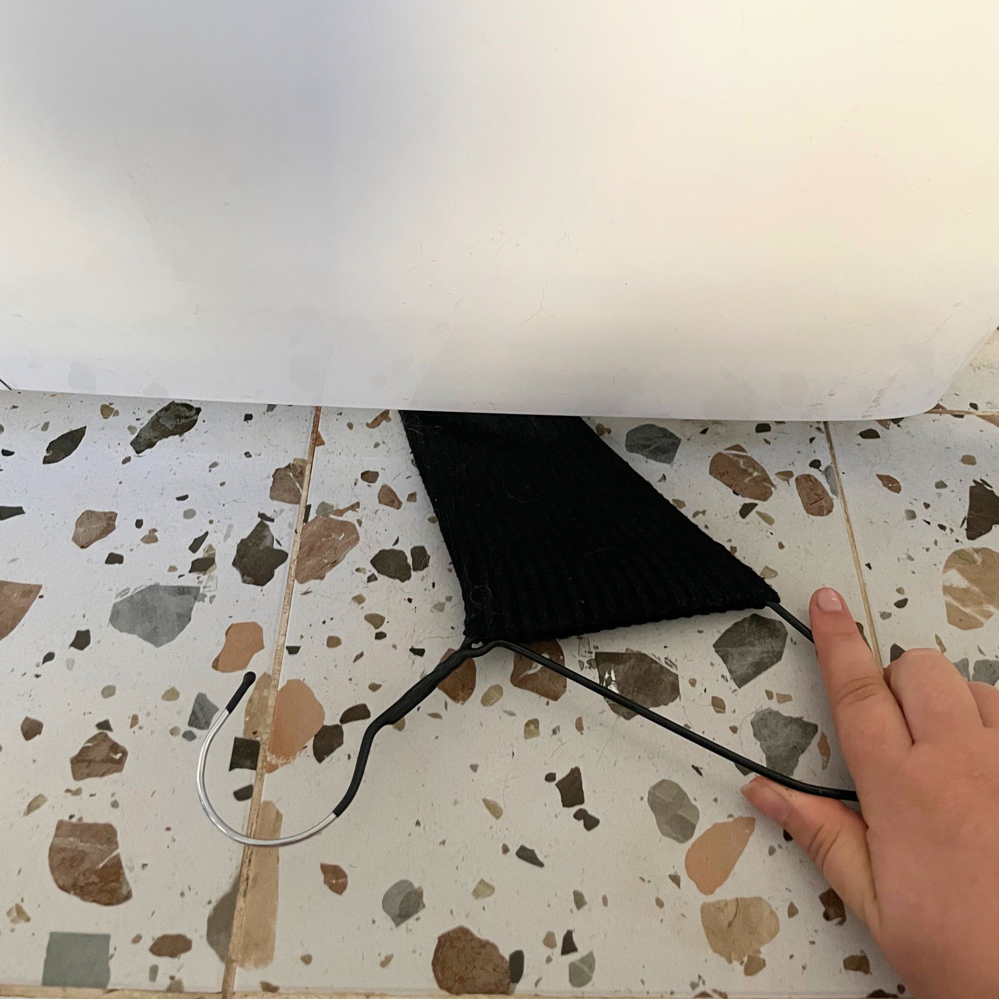 Using a wire hanger with a sock over it to clean underneath a washing machine