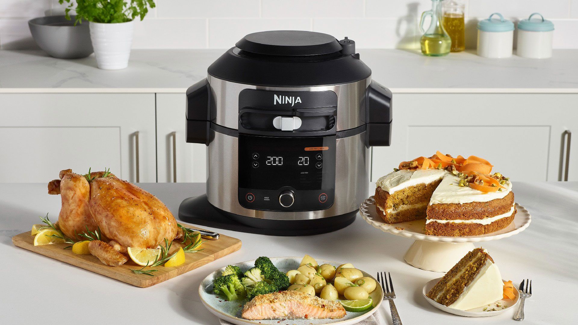 Ninja air fryer and multicooker on a white kitchen countertop next to fries and a cake made using the small appliance