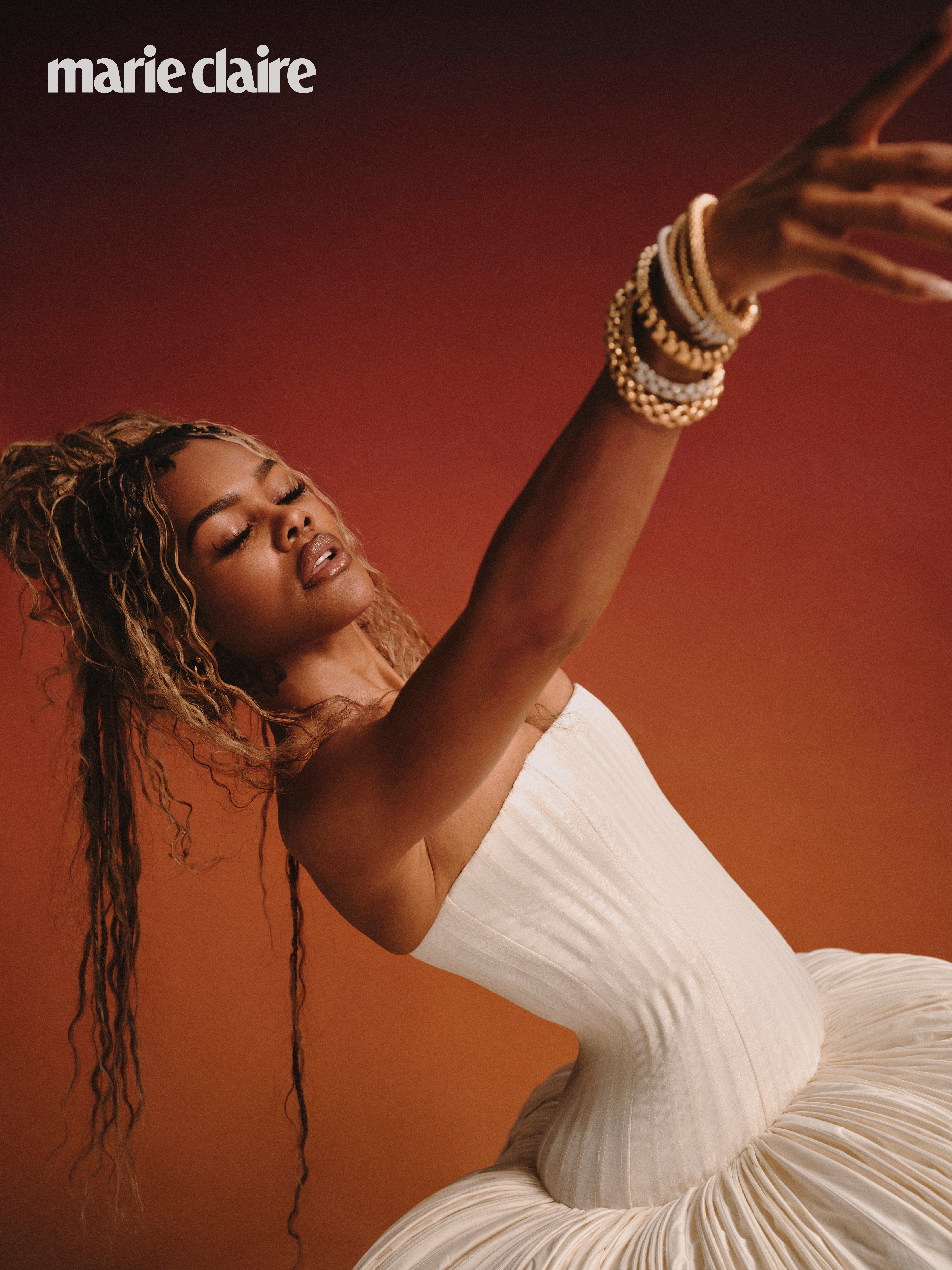 Teyana Taylor in an ivory dress reaching for the camera