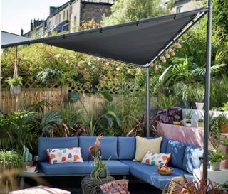 sail shade in a small garden or patio area with outdoor sofas and cushions