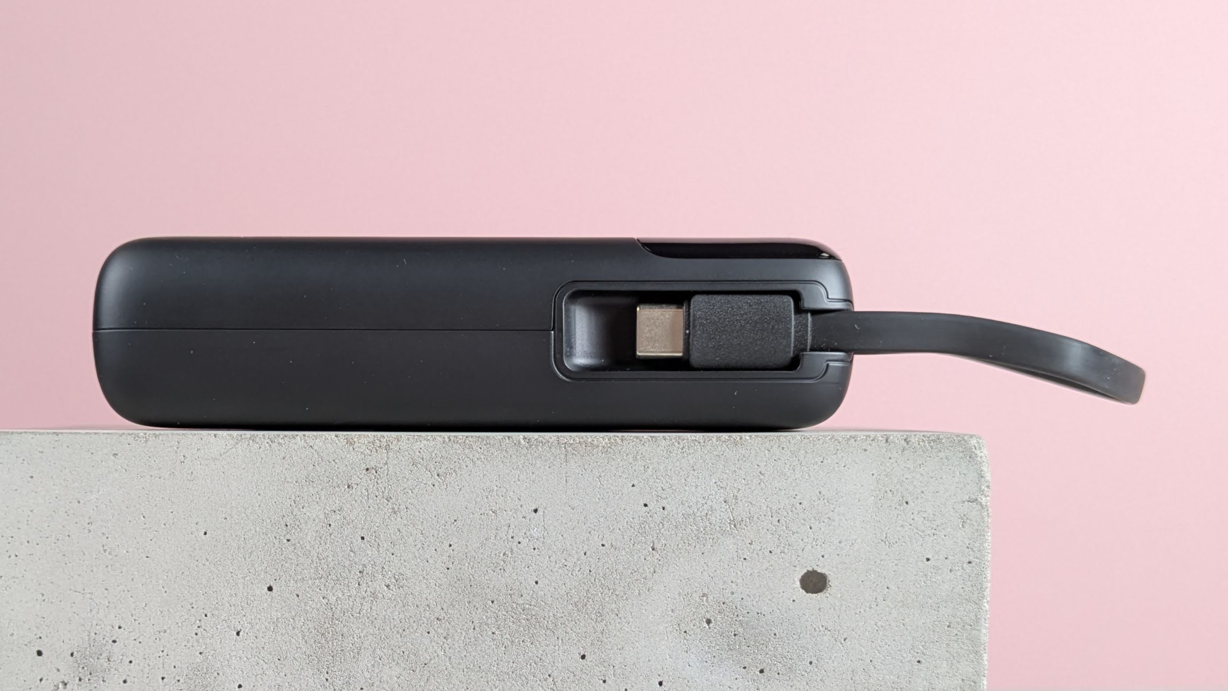 Side view of INIU P51L-E1 Power Bank, on plinth with pink background