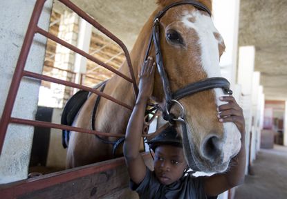 Judeley Hans Debel, whose right leg is a prosthesis, caresses Tic Tac after riding her at the Chateaublond Equestrian Center in Petion-Ville, Haiti.