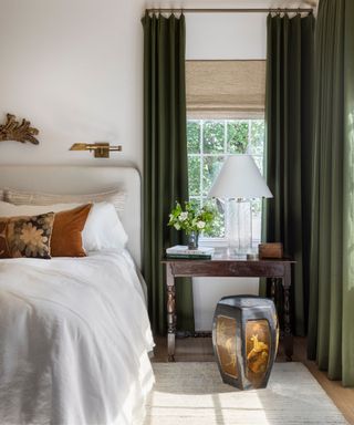 small bedroom with green curtains that are hung tall to the ceiling