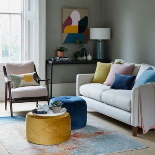 neutral living room with coloured footstools cushions and rug
