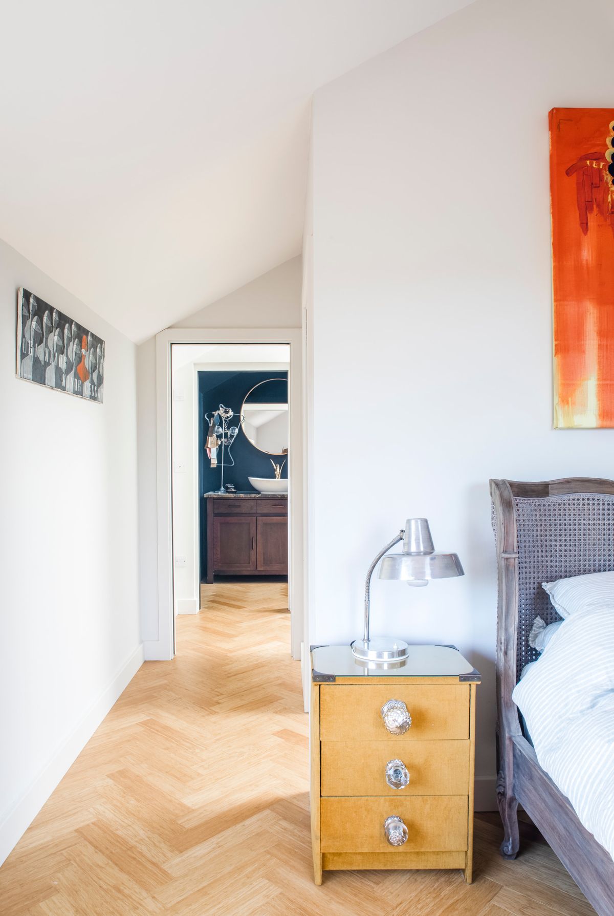A bright bedroom with white walls and light herringbone flooring