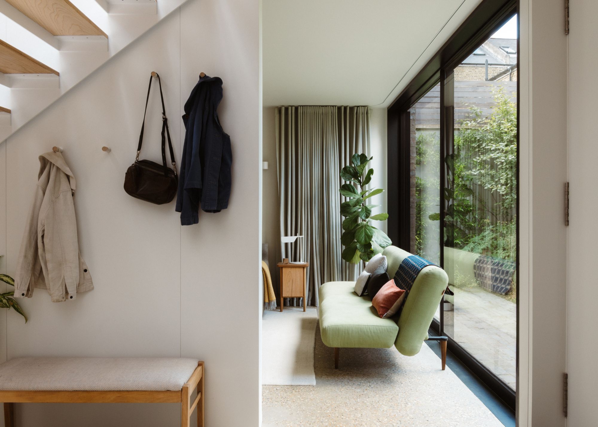 modern living room with sliding glass doors overlooking garden, minimalist light green sofa and light gray curtains