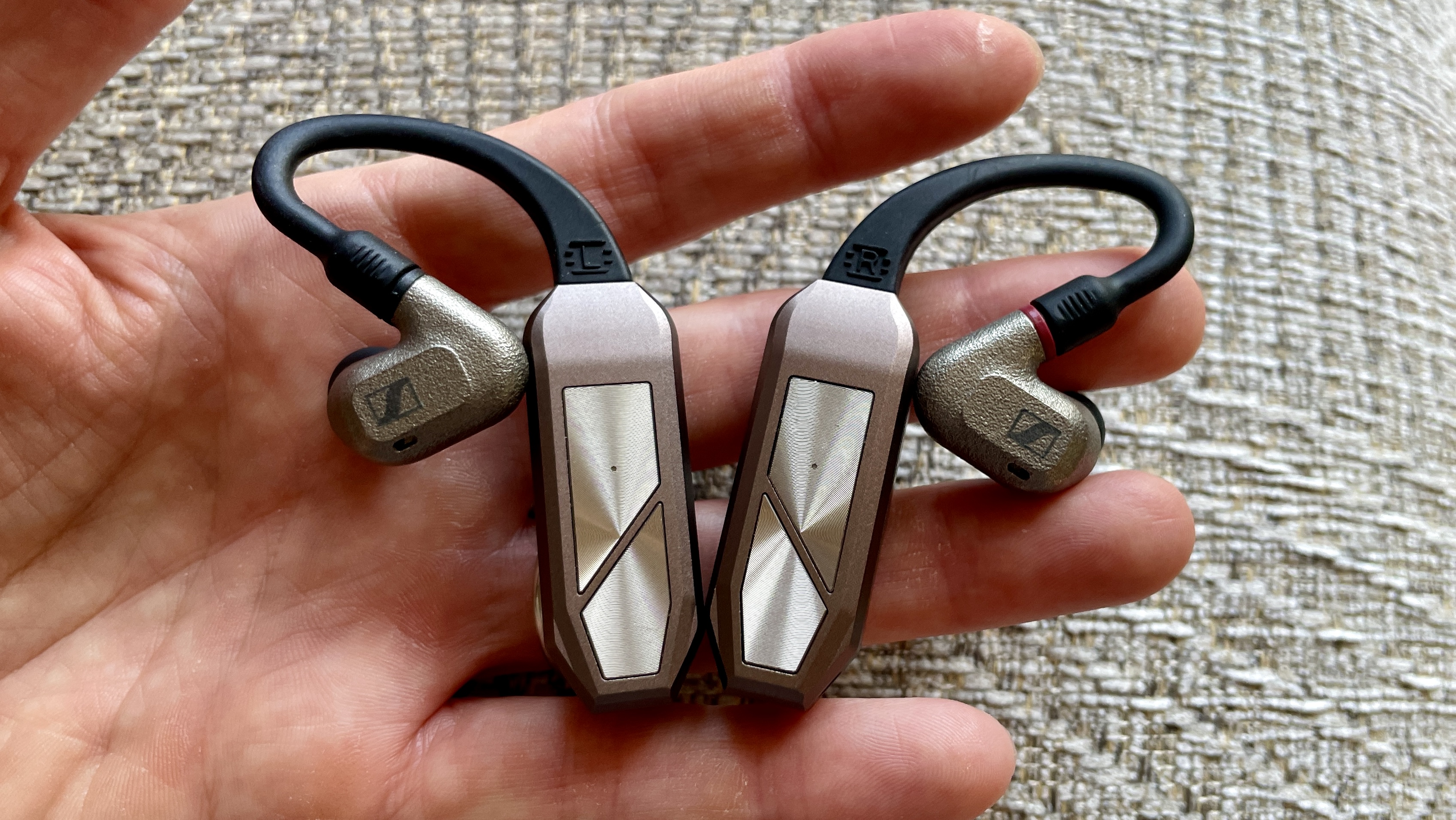 iFi Go Pod in a hand, with high-end wired earbuds and in the case, which accepts even larger earbuds