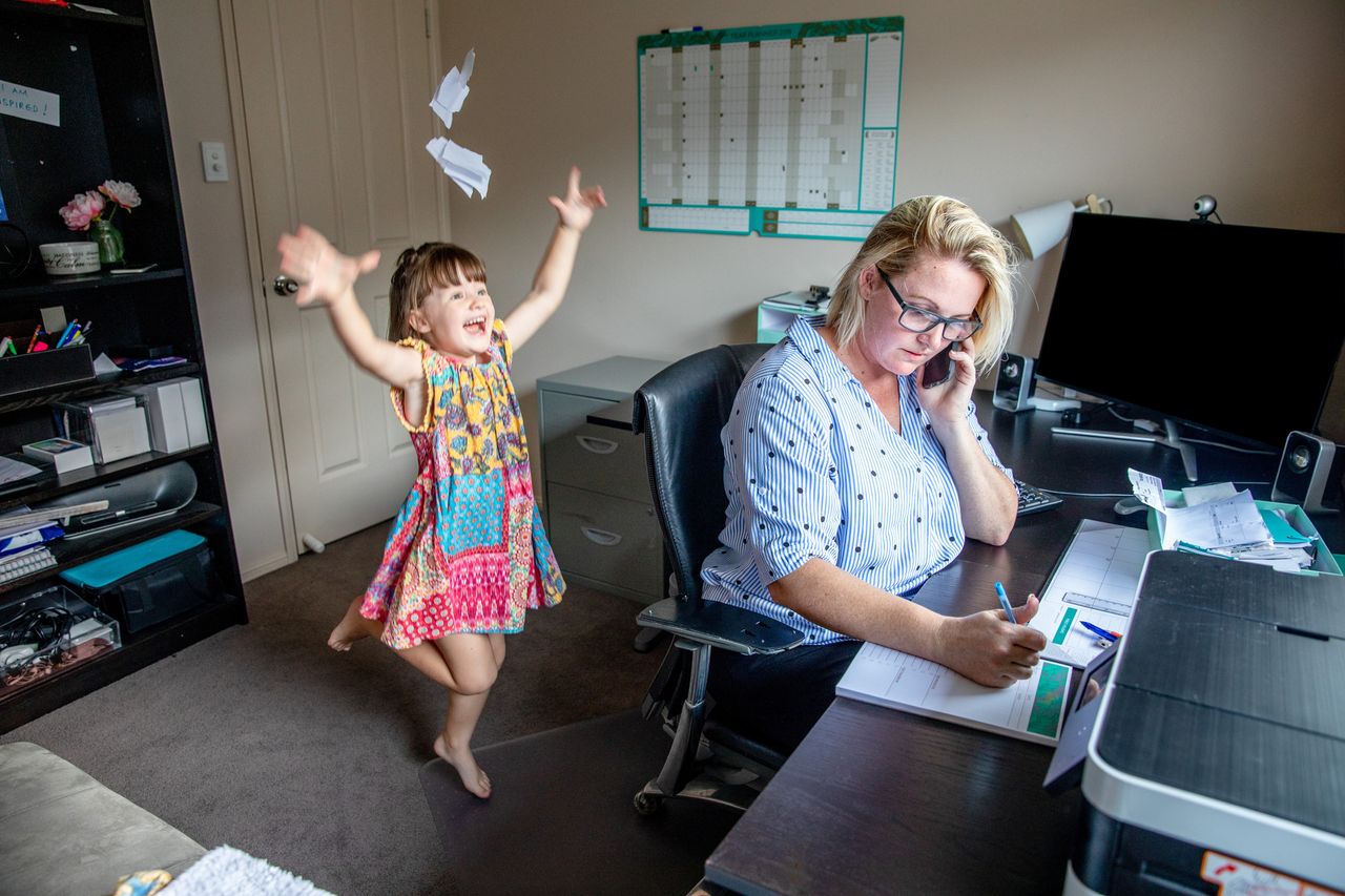 Young mother with a baby and a dog, sitting on the floor and working. High angle of view.