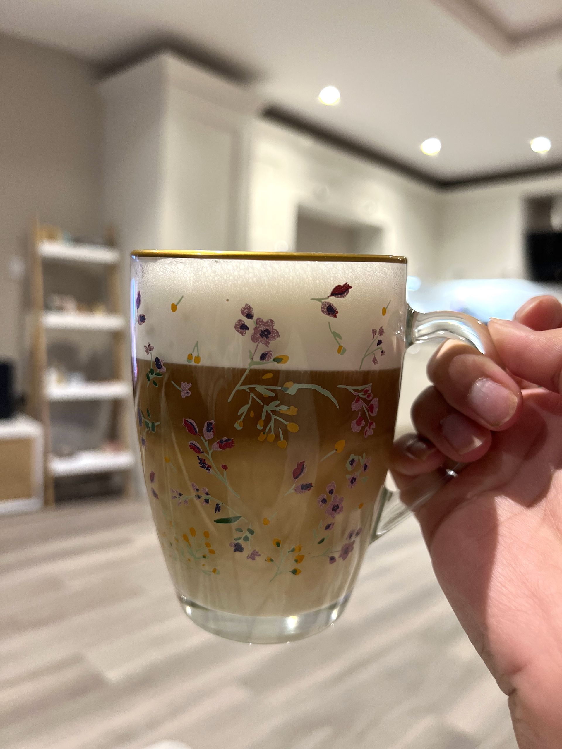 Gambar latte dalam cangkir kaca bermotif bunga yang dibuat dengan Breville One Touch Coffee Maker