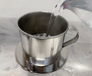 Pourinng water into Vietnamese phin coffee maker