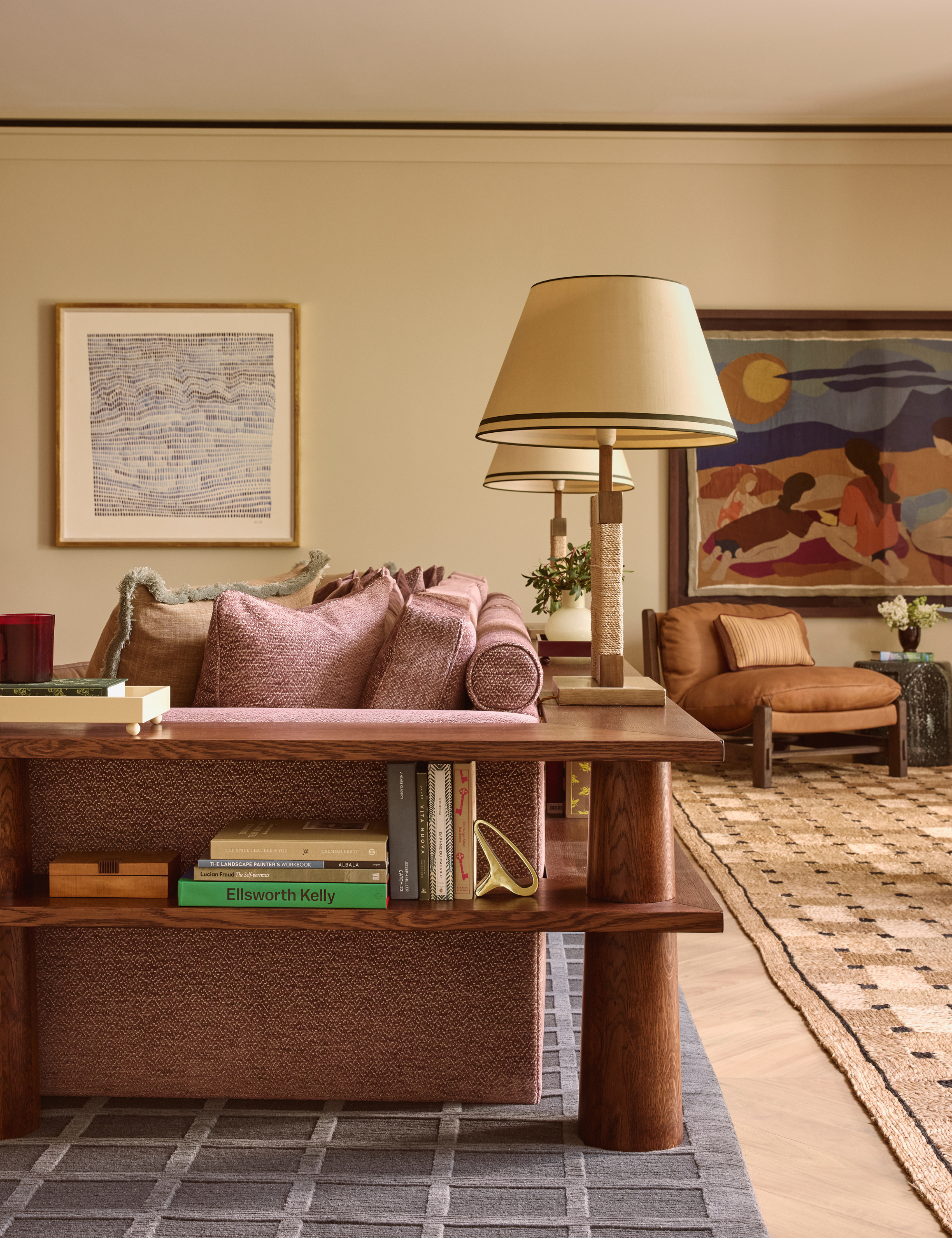 Snug area of a prestigious Mayfair residence defined by low-slung wooden joinery, which stores stacks of books and linen-shaded table lamps
