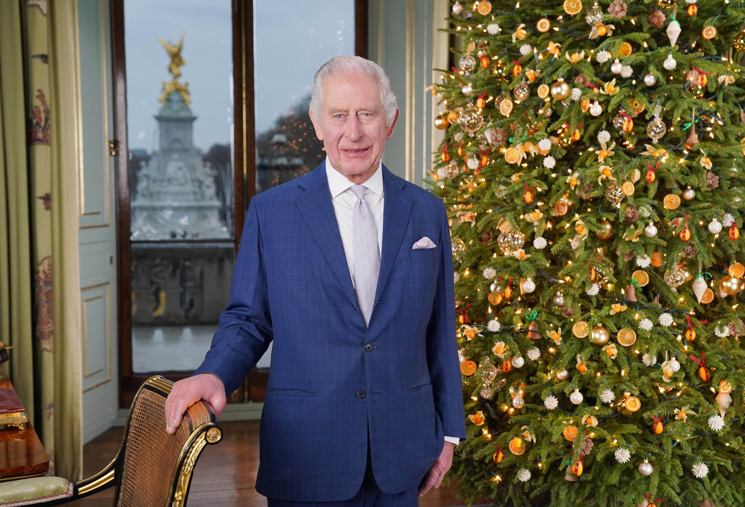 King Charles standing next to a Christmas tree