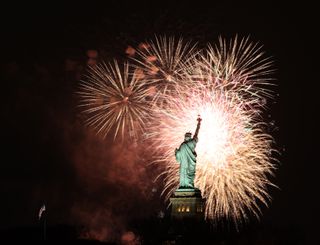 The Statue of Liberty illuminated against a dark sky, surrounded by an explosion of colorful fireworks celebrating the New Year.