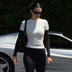 Kendall Jenner posing next to her vintage Ferrari 512 TR sports car wearing an Adanola layered T-shirt and capri leggings with The Row flats.