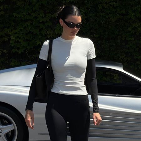 Kendall Jenner posing next to her vintage Ferrari 512 TR sports car wearing an Adanola layered T-shirt and capri leggings with The Row flats.