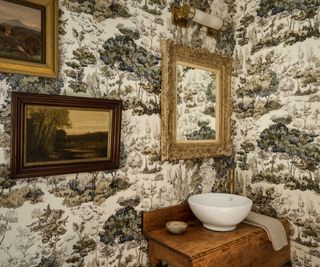 powder room with toile de jouy wallpaper in brown with vintage wooden vanity