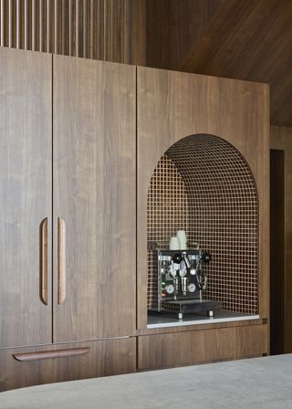 arched coffee niche in a wood cabinet with brown mosaic tiles around it