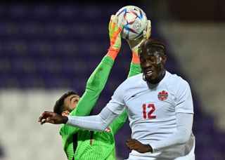 Qatar's goalkeeper Saad Al Sheeb (L) makes a save from Canada's forward Ike Ugbo during the friendly football match between Qatar and Canada in Vienna on September 23, 2022.