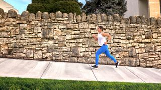 Woman running uphill wearing Garmin Forerunner 55 watch