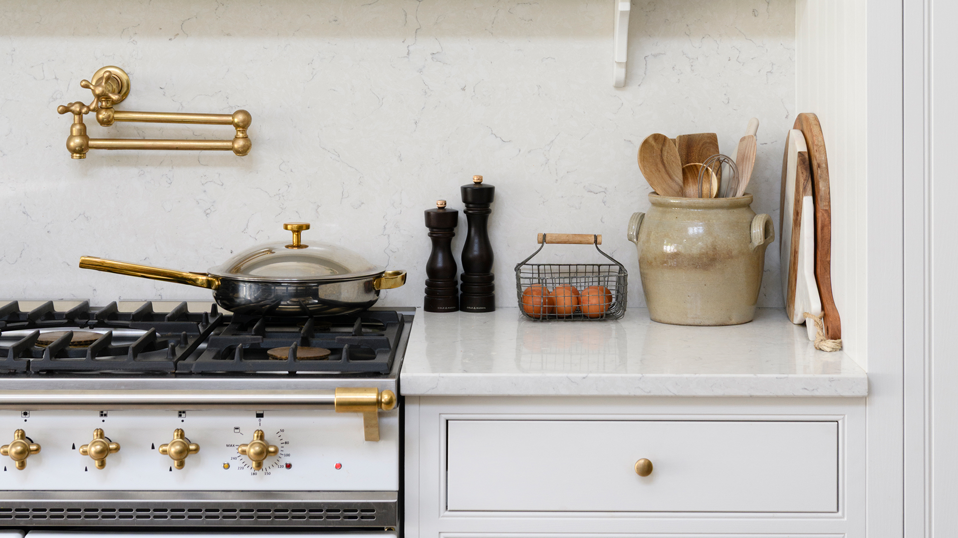 Luxury white marble kitchen with a gold pot wash tap above a white and gold range cooker