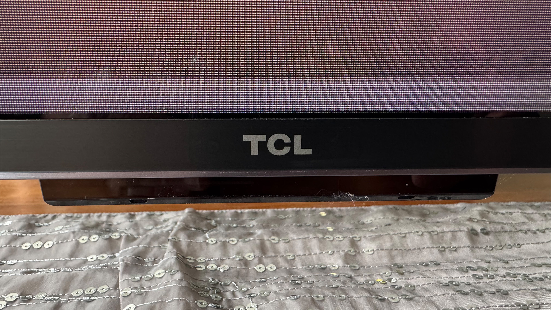 TCL 98C7K 98-inch TV detail of bottom edge of set and TCL logo