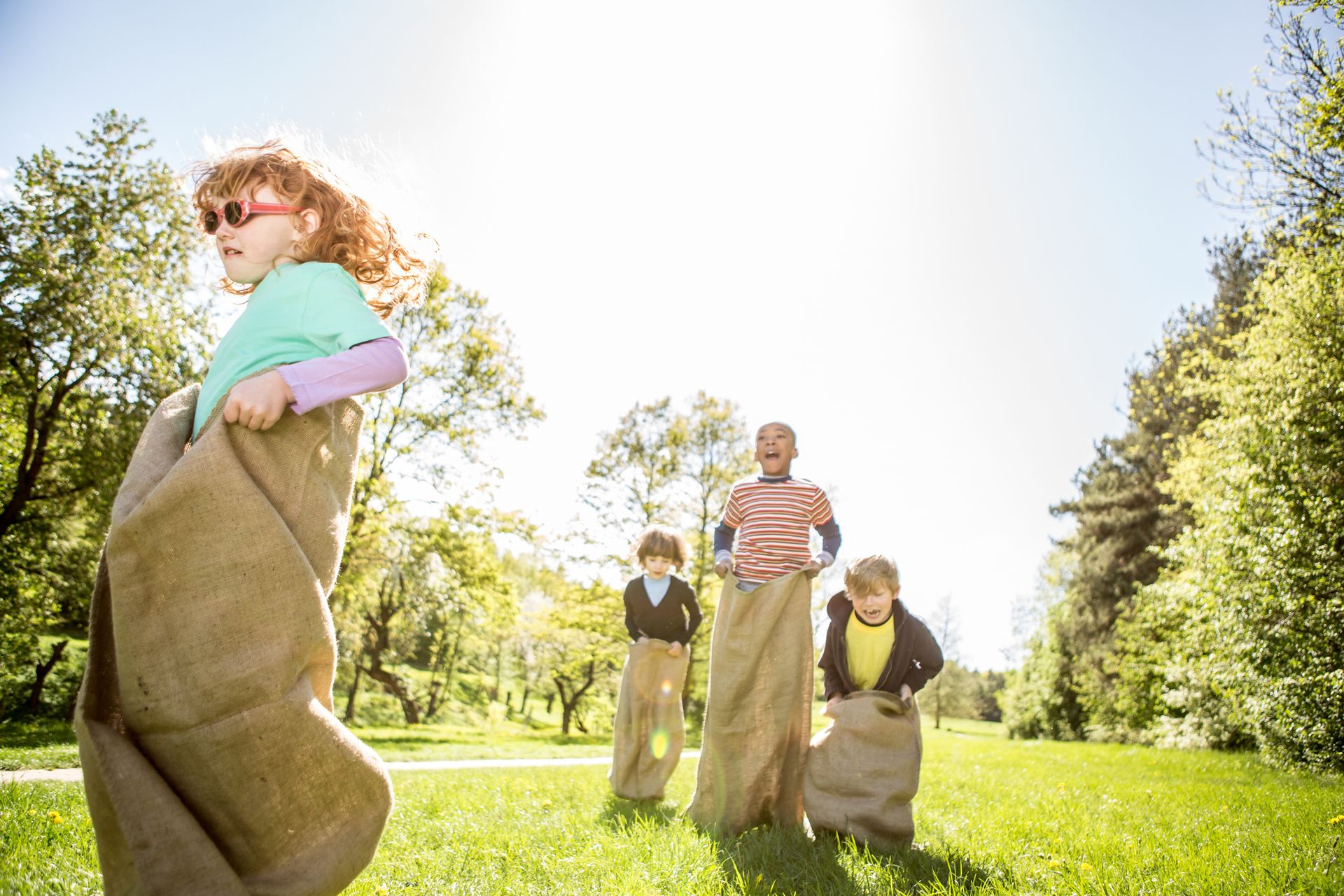 Kids participate in a sack race, laughing and shouting.
