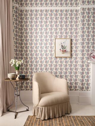 Neutral living room with armchair and side table and patterned wallpaper