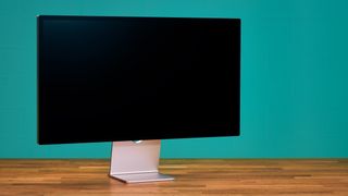 An Apple Studio Display photographed on a wooden desk