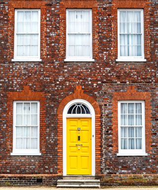 red brick house exterior with bright yellow front door