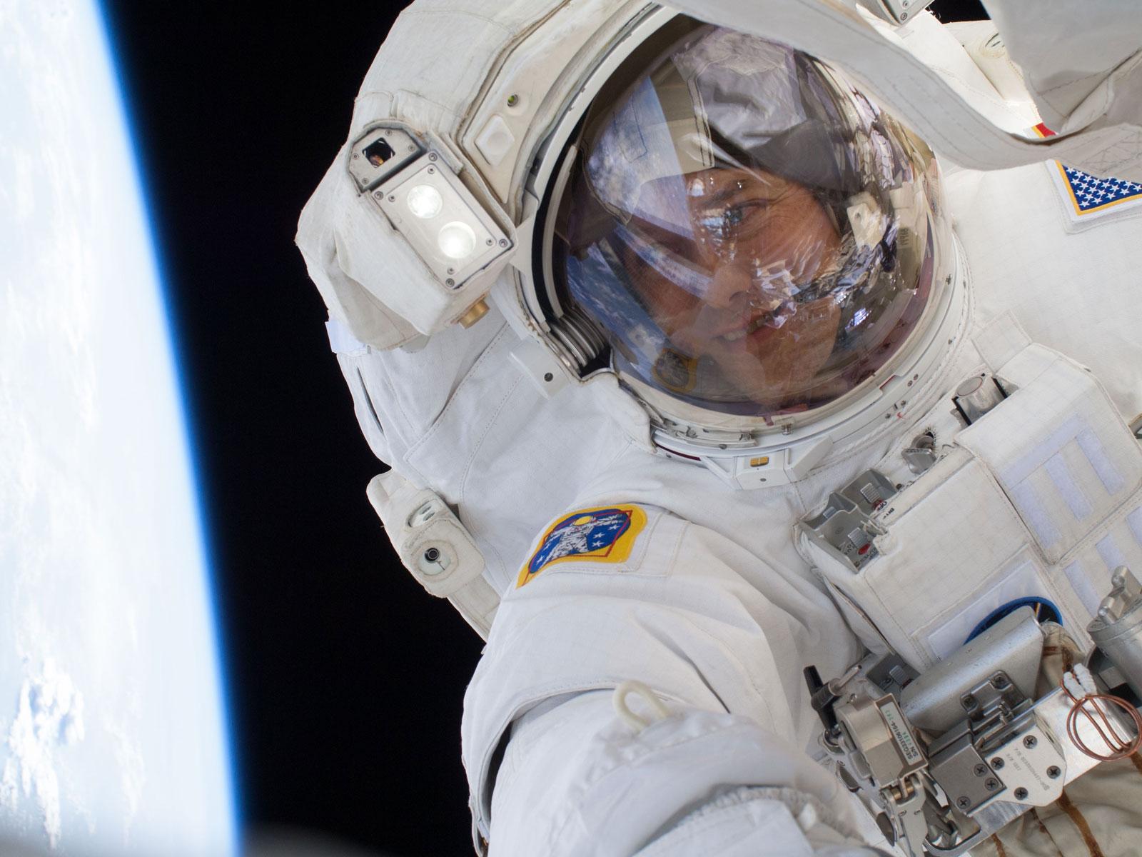 astronaut in spacesuit with the curve of blue earth to the side