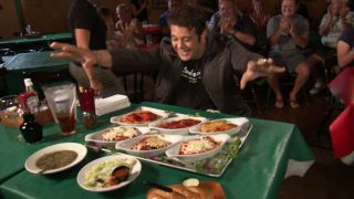 Adam Richman marveling at a massive table of italian food