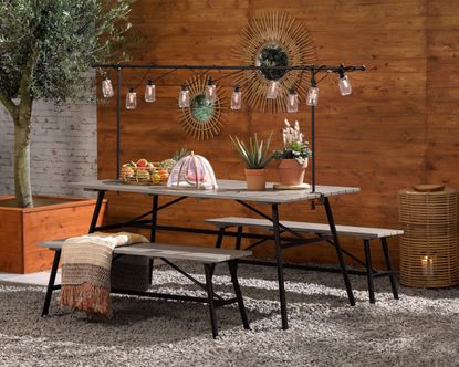 An example of how much does outdoor lighting cost showing a patio with a dining table, benches and outdoor string lights