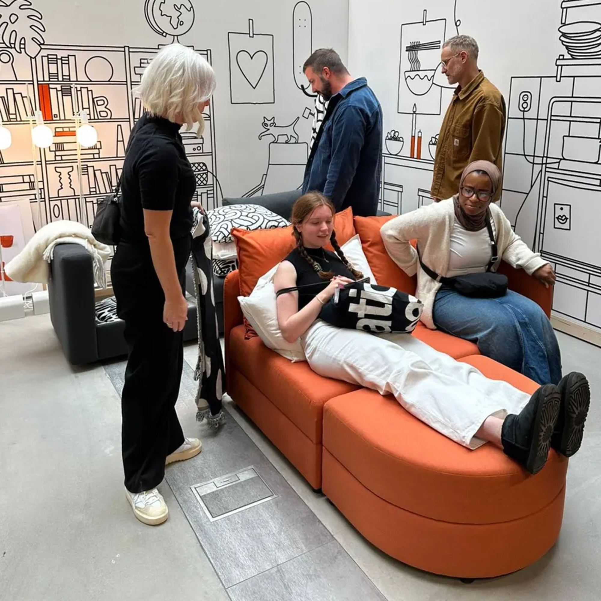 The orange IKEA LINDAKRA sofa bed being sat on by press during IKEA's 2024 press show