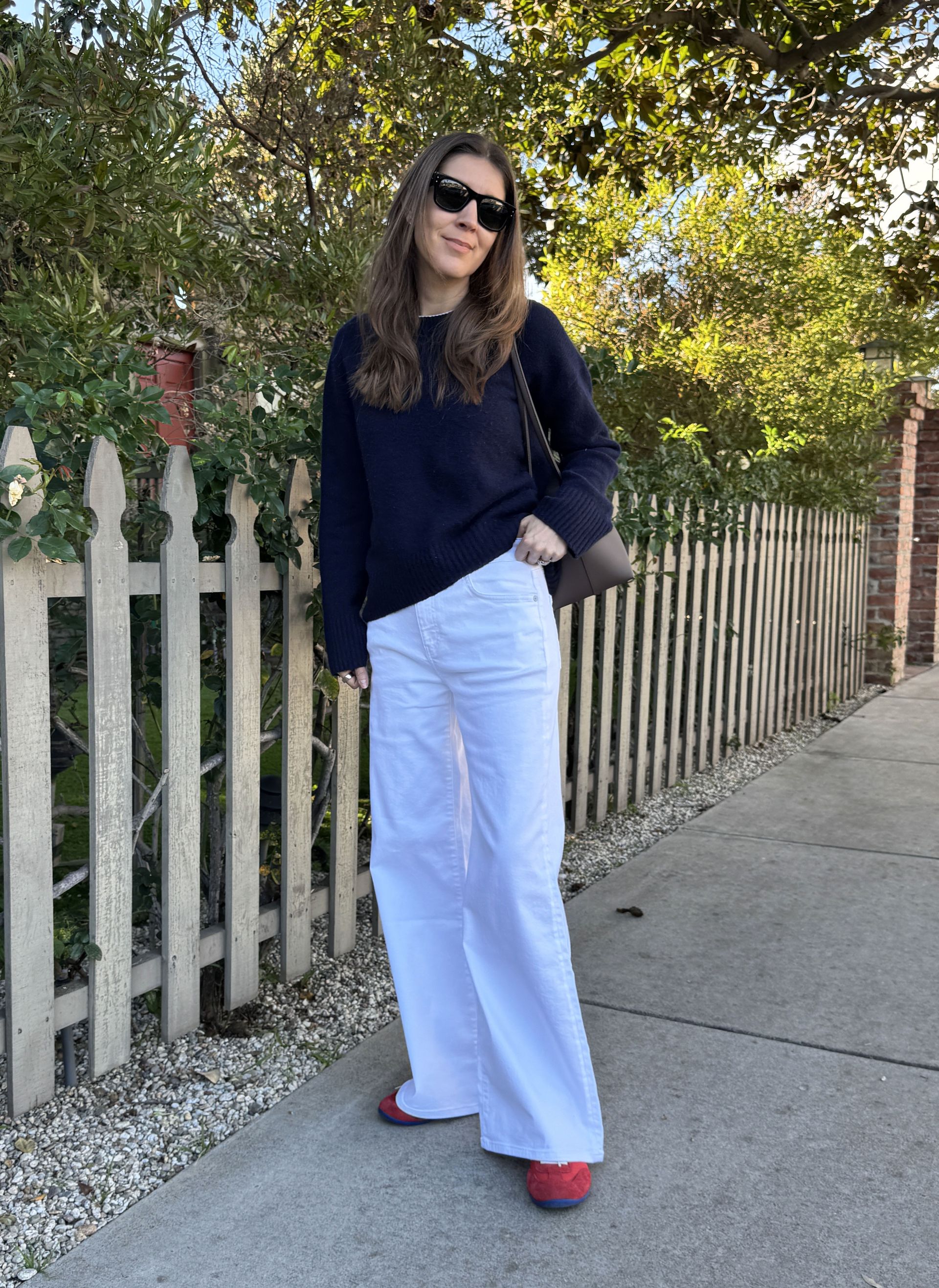 Fashion editor Judith Jones in white relaxed AG jeans, a navy sweater, and red sneakers.