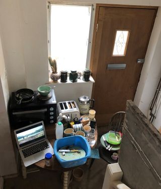 My temporary kitchen setup in my hallway with mini cooker on a tble and plastic washing up bowl for dirty dishes