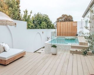 An above ground tiled pool with light wood deck