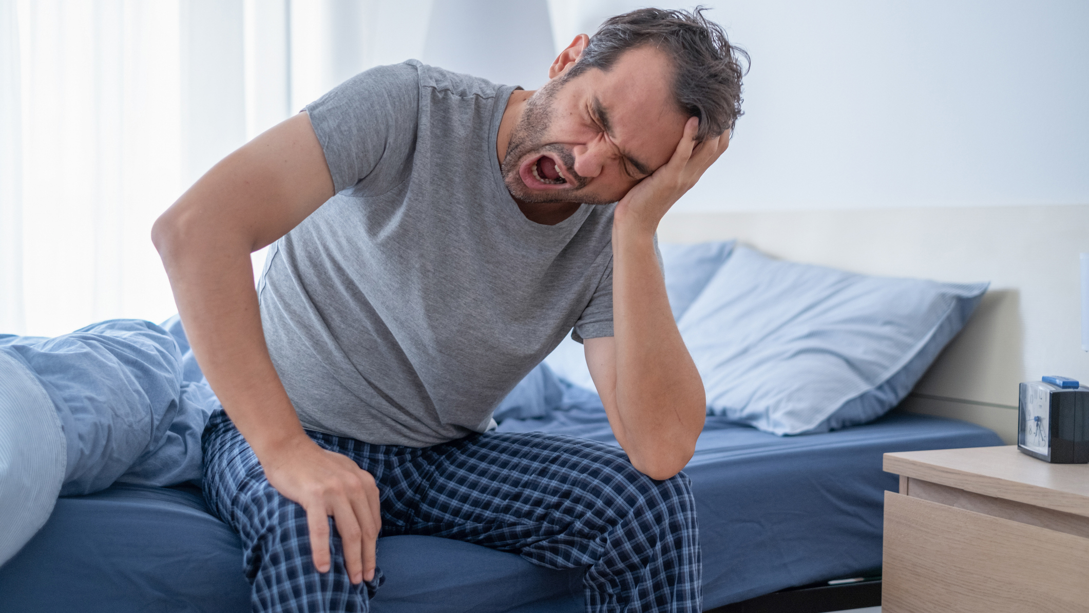A man sits in bed at night because his restless legs keep him awake and affecting his sleep.