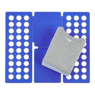 Blue four-piece plastic folding tool that looks like a rectangle with side and bottom wings. A pile of neatly folder jersey tops demonstrates uniformity of the folding with this tool