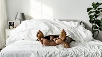 feet of couple lying in bed